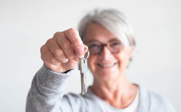 a middle aged woman holding a key up to the camera
