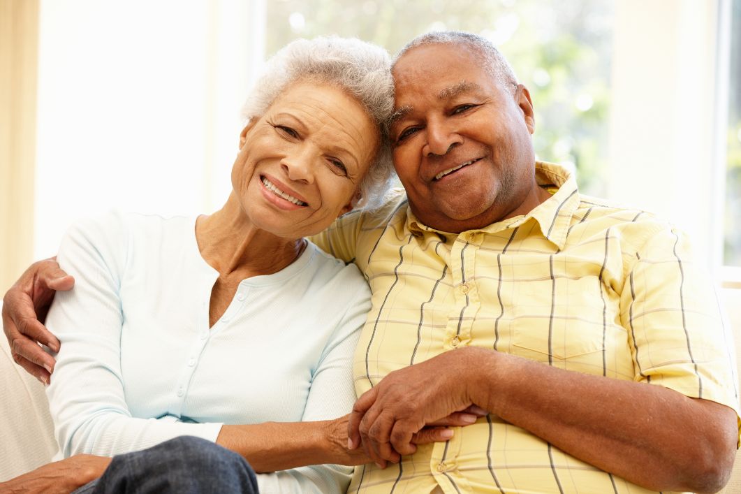 an elderly couple smiling at the camera while holding hands